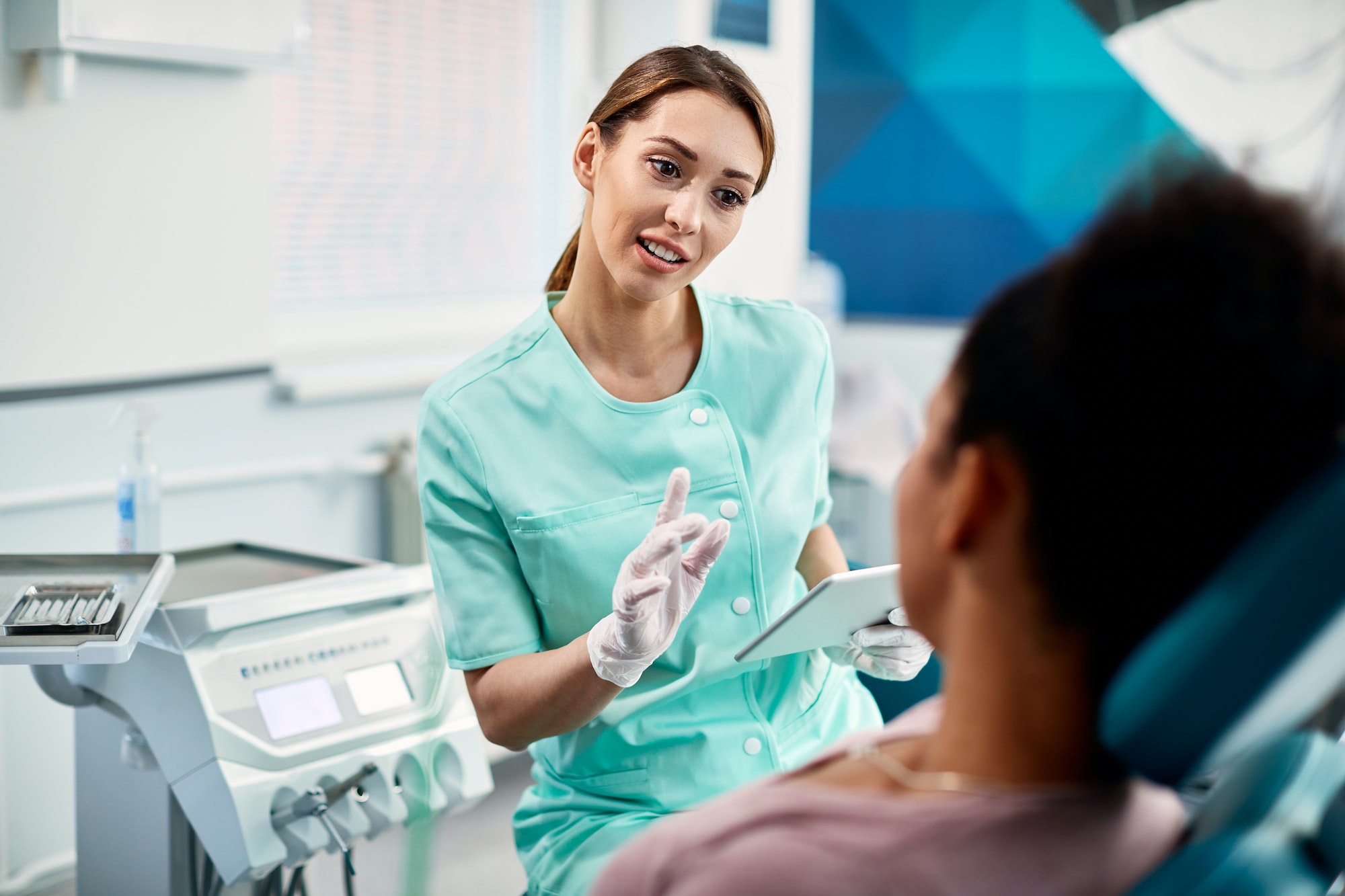 Young female dentist communicating with patient before dental procedure at dentist's office.